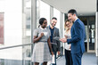 © UWE_UMSTAETTER/Westend61 - Smiling business people with tablet talking on office floor
