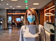 © Zeljko Dangubic/Westend61 - Senior woman wearing protective face mask standing in hotel lobby