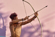 © victor espadas/Westend61 - Barechested young man with bow and arrow outdoors