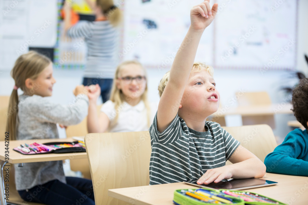 Schoolboy with tablet raising his hand in class Stock Photo | Adobe Stock