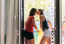 Female Lesbian Nuzzling Nose While Standing In Balcony At Home