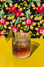 Cocktail Liquor Kept On Yellow Table Against Flower Background