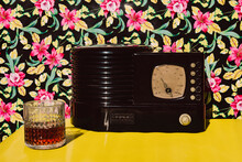 Studio Shot Of Cocktail Liquor And Old Radio On Table Against Flower Background