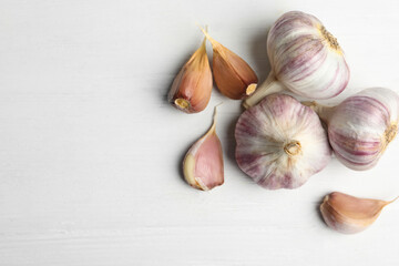 Fresh organic garlic on white wooden table, flat lay. Space for text