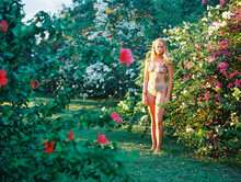 Blonde Teenager In Bikini Standing In Flowering Garden Bushes
