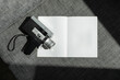 © Nicole Mason/Stocksy - analogue super 8 film camera and blank white book pages in direct sun light