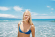 © wendy laurel/Stocksy - Blonde girl in blue bikini at sunshiney beach in summer with sunglasses and rainbow towel