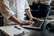 © Sofie Delauw/Stocksy - Crop chef browsing laptop in kitchen