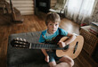© irina polonina/Stocksy - A young boy is learning to play the guitar.