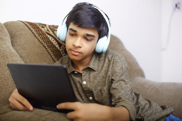 Wall Mural - Indian young boy using digital tablet while attending the online classes at home	
