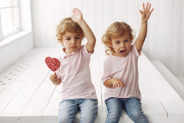 Sticker - Children with candy in a studio. Little girl with her brother. Boy in a pink t-shirt