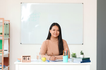 Sticker - Asian female teacher sitting at table in classroom