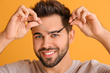 Sticker - Young man with tools for eyebrow correction on color background