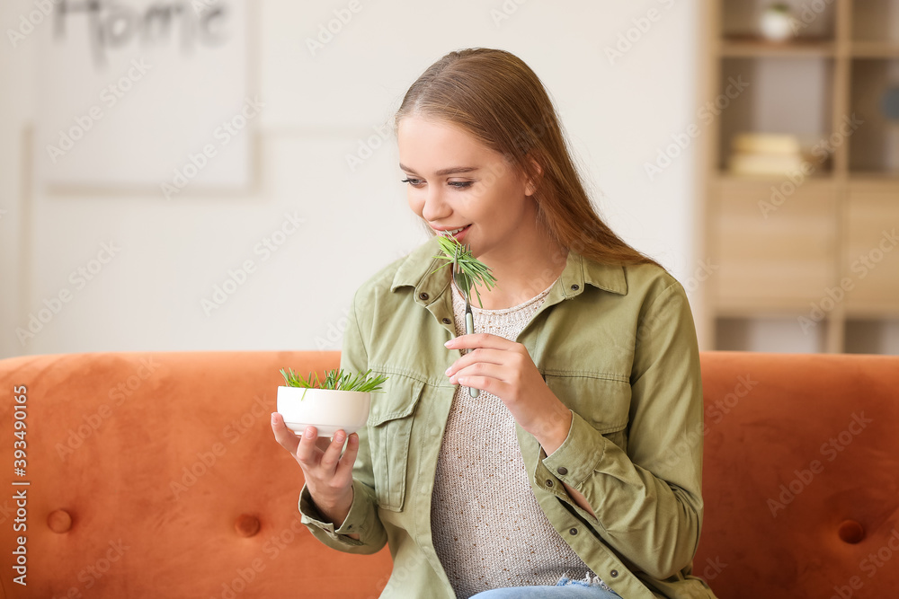Young woman eating wheatgrass at home