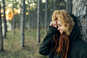 cheerful woman in a jacket near a tree on nature rest