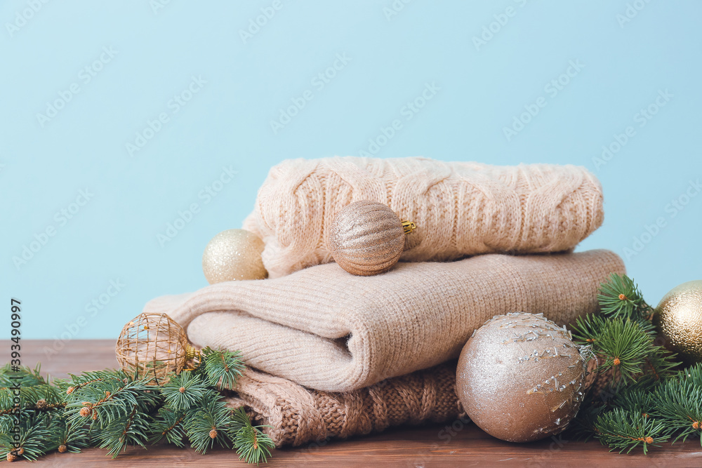 Christmas composition with stylish clothes on table against color background