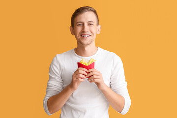 Young man with french fries on color background