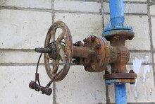 Old Damaged And Rusty Iron Oil Pipe Valve Wheel. Metal, Pipeline And Mechanic Concept. An Old Iron Valve On A Gas Pipe. A Valve To Cover The Pipe With A Round Handle