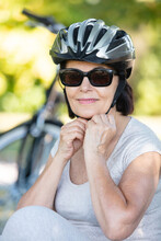 Elderly Woman Putting On A Bicycle Helmet