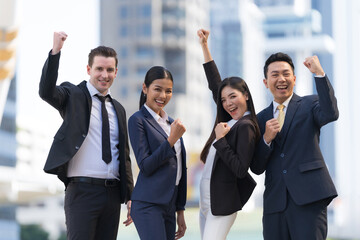 Four executives in a row, Business team standing and cheering in front of modern office