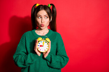 Canvas Print - Photo of young attractive pretty charming girl pout lips look copyspace hold clock isolated on red color background