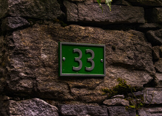 Sticker - Closeup shot of the green sign 33 on the stone wall