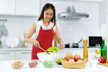 Wall Mural - Woman mixing salad in white bowl.