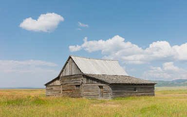 Wall Mural - Early settler homestead isolated in the vast prairie and blue sky. Jackson, USA.