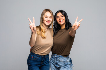 Wall Mural - Portrait of a two girlfriends women showing two fingers sign on gray background