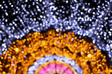 Christmas lights, defocused colorful abstract background. Blurred bokeh with golden, pink and blue shining lights, New Year holiday texture, decorations on the night street