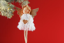 Handmade Christmas Angel Toy On A Christmas Tree On A Red Background.