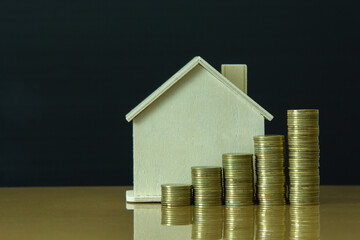 golden coin stack growth up with wooden house in background, saving concept