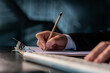 © VideoFlow - Closeup of office manager in suit holding a pencil with right hand, writing on a blank paper in the clipboard. Planning, office work, no face. Concept of contract