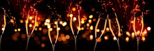 Celebrations With Champagne In Front Of Red Glittering Fireworks Sky And Golden Bokeh. Horizontal Background For Silvester And Wedding. Special Occasion Concept.