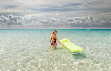 Wall Mural - young woman in a one-piece swimsuit in the sea with an inflatable mattress