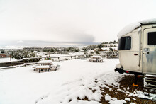 Fresh Snow At A Campground Hanging Off Picnic Tables And RV And Covering Trees And Mountains In The Background, Lander, Wyoming