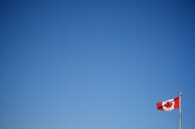 Low Angle View Of Canadian Flag Against Clear Blue Sky