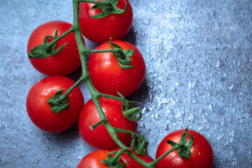 Fresh ripe red cherry tomatoes covered with drops of water on a marble background with copy space