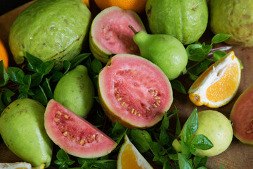 Wall Mural - sliced and whole guava and tangerine fruits with Basil leaves