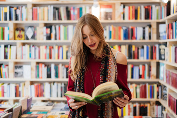 Beautiful blonde woman reading a book in a bookstore.