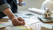 © PIC SNIPE - Interior designer choosing color in color swatch samples chart for house coloring selection in office with blueprint. Construction concept.