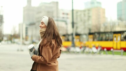 Wall Mural - young woman walking on the city street holding cup of coffee