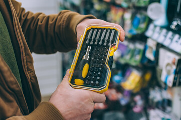 Wall Mural - A man in a supermarket holds a set of screwdrivers.