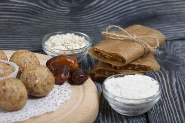 Canvas Print - Dried fruit and oatmeal sweets. Nearby ingredients for their preparation. On black pine boards.