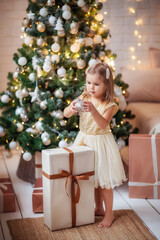 Wall Mural - child girl in the new year's interior at the Christmas tree, playing, waiting for the new year, gifts, holiday, happiness, lights, garlands