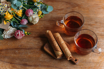 Still life. Table with mugs of tea, cookies and flowers