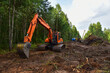 Excavator clearing forest for new development. Orange Backhoe modified for forestry work. Tracked heavy power machinery for forest and peat industry. Construction Gas Pipeline Project