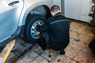 Mechanic changing car wheel in auto service workshop