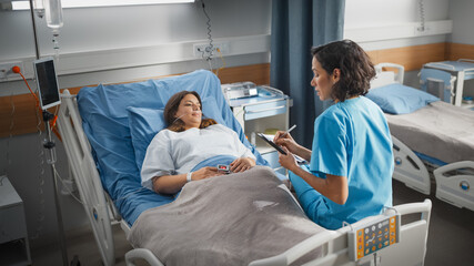 Wall Mural - Hospital Ward: Friendly Hispanic Head Nurse Fills Medical History Form, Talks to Female Patient Recovering in Bed. Professional Nurse Helps Happy Woman Get Better after Surgery.