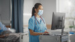 © Gorodenkoff - Hospital Ward: Professional Experienced Chinese Head Nurse / Doctor Wearing Face Mask Uses Medical Computer, Checking Patient's Medical Data. In the Background Patient Recovering on Bed.